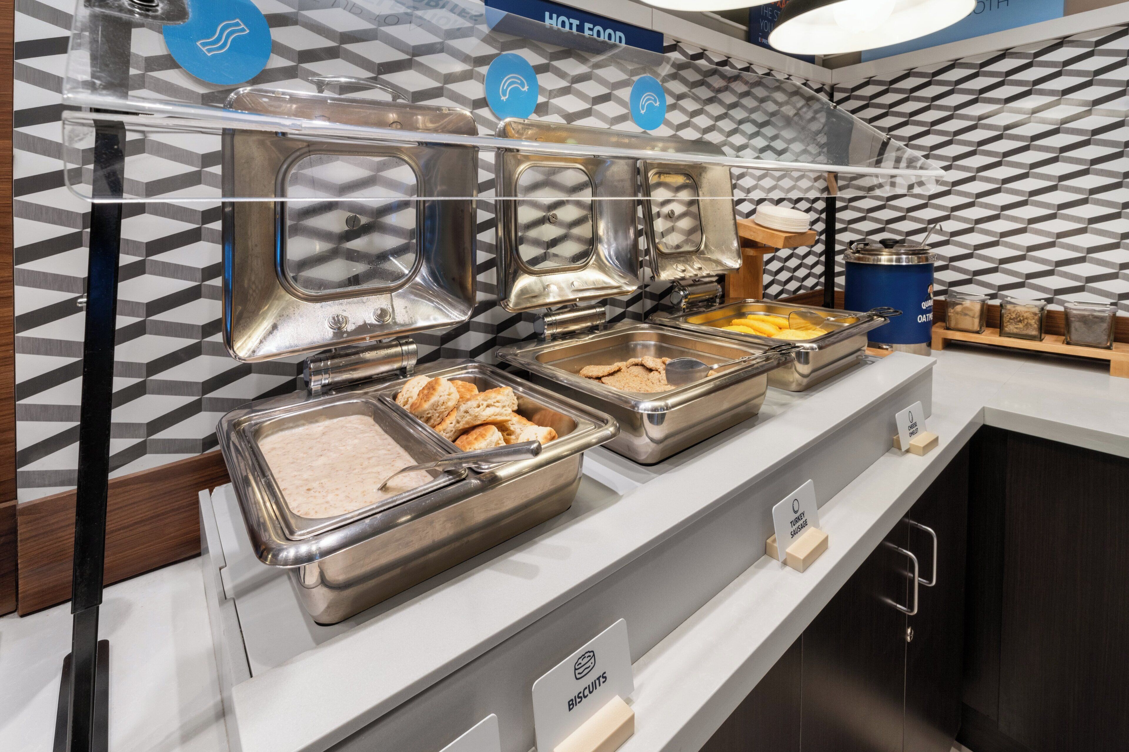 A buffet setup with labeled food sections including turkey sausage, biscuits, and other items.