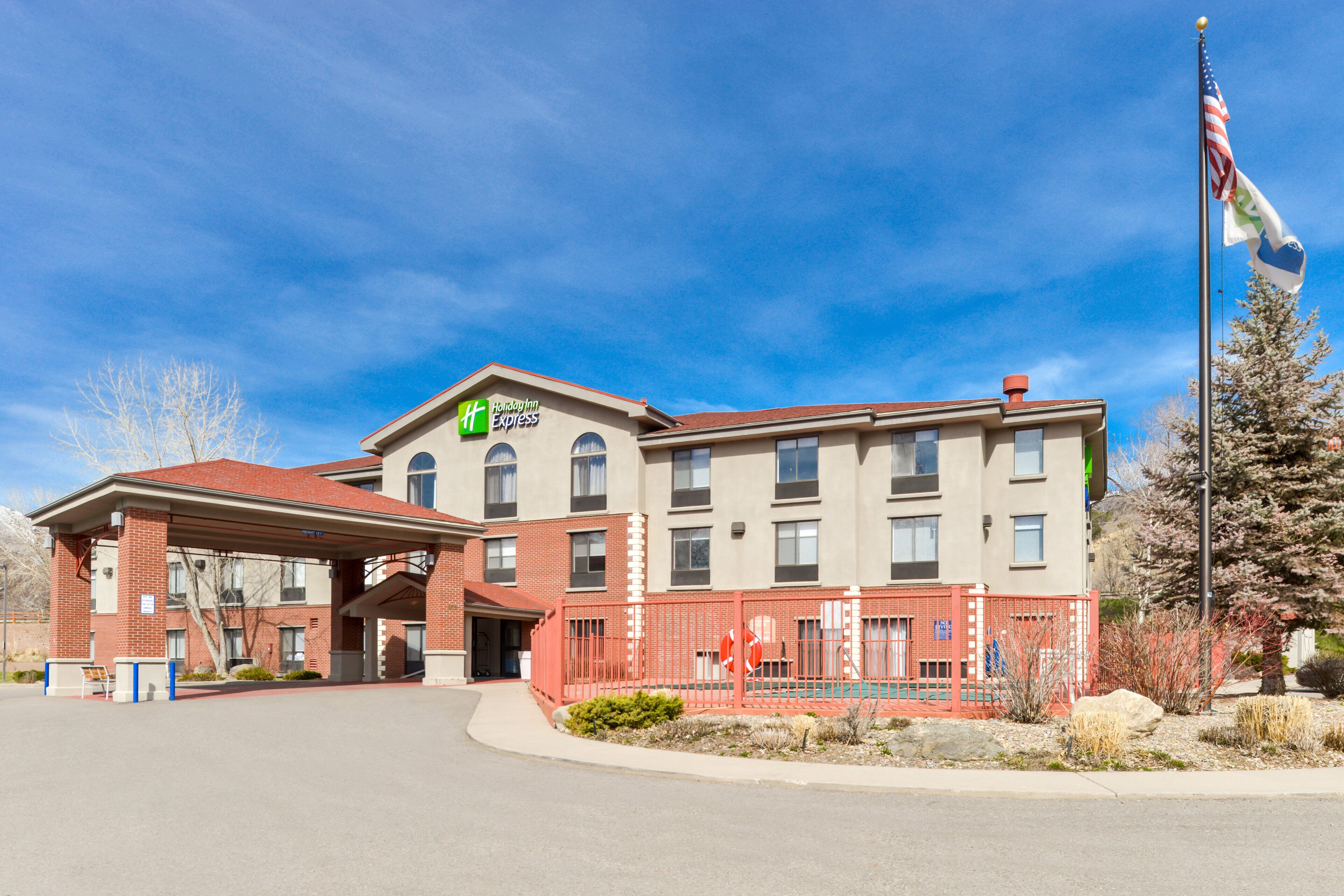 A Holiday Inn Express building with a brick facade, a covered entrance, and a flagpole with a flag.