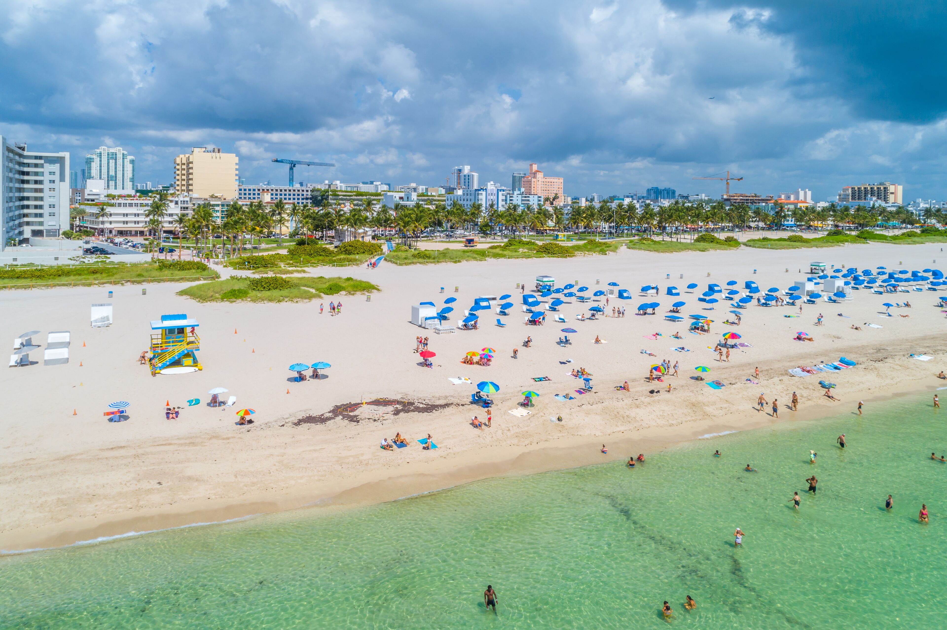 A beach with numerous umbrellas and people.