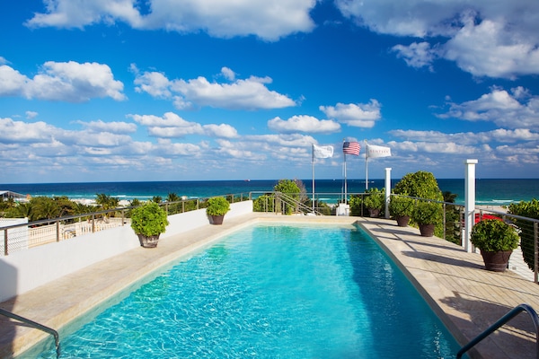Una piscina al aire libre, sombrillas, sillones reclinables de piscina