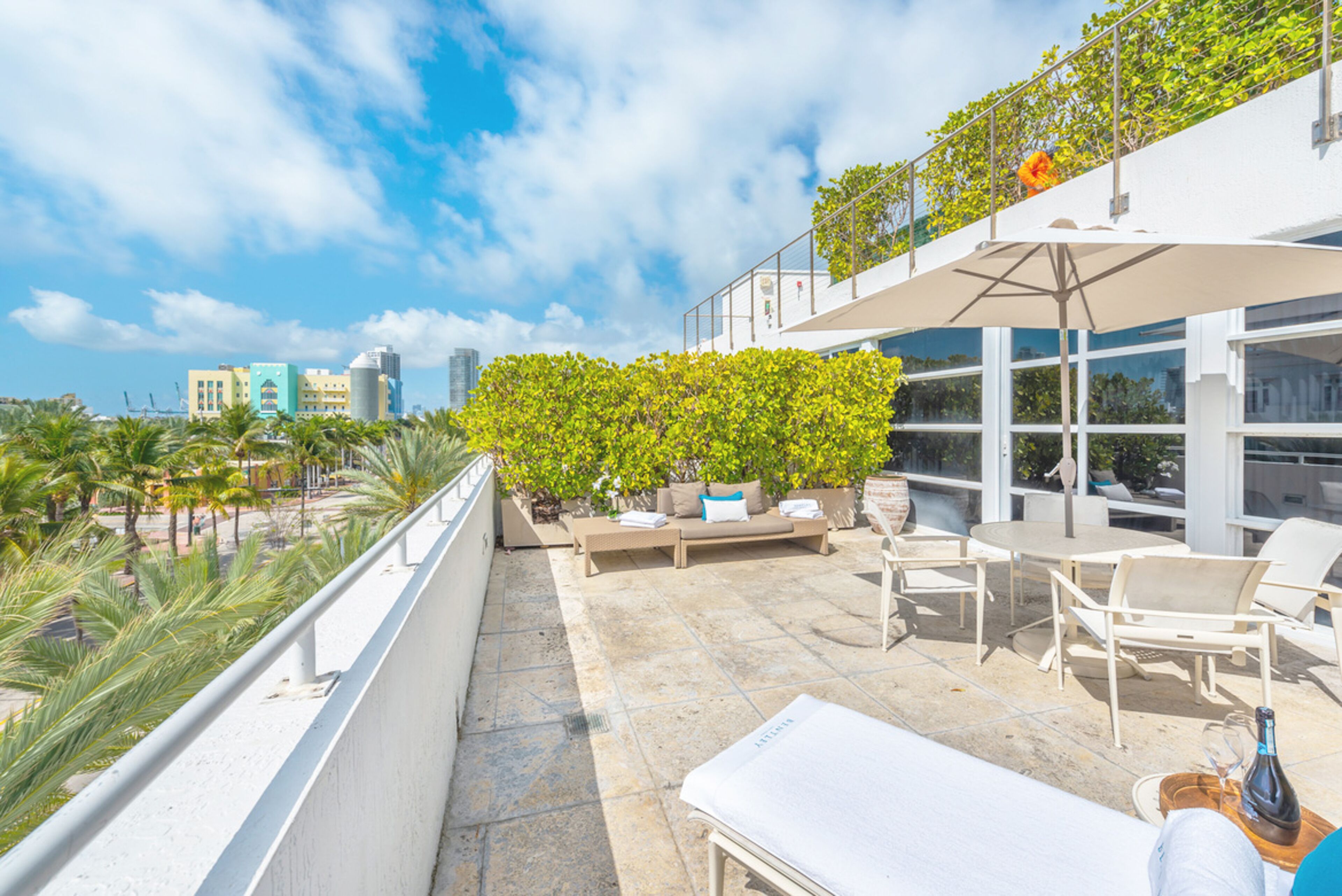 A rooftop terrace with outdoor furniture, a dining area, and a view of the cityscape.