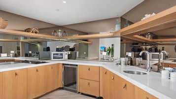 A modern kitchen with wooden cabinets, a dishwasher, a sink, and a countertop with various appliances.