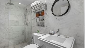 Un baño moderno con ducha de vidrio, inodoro, lavamanos y espejo.