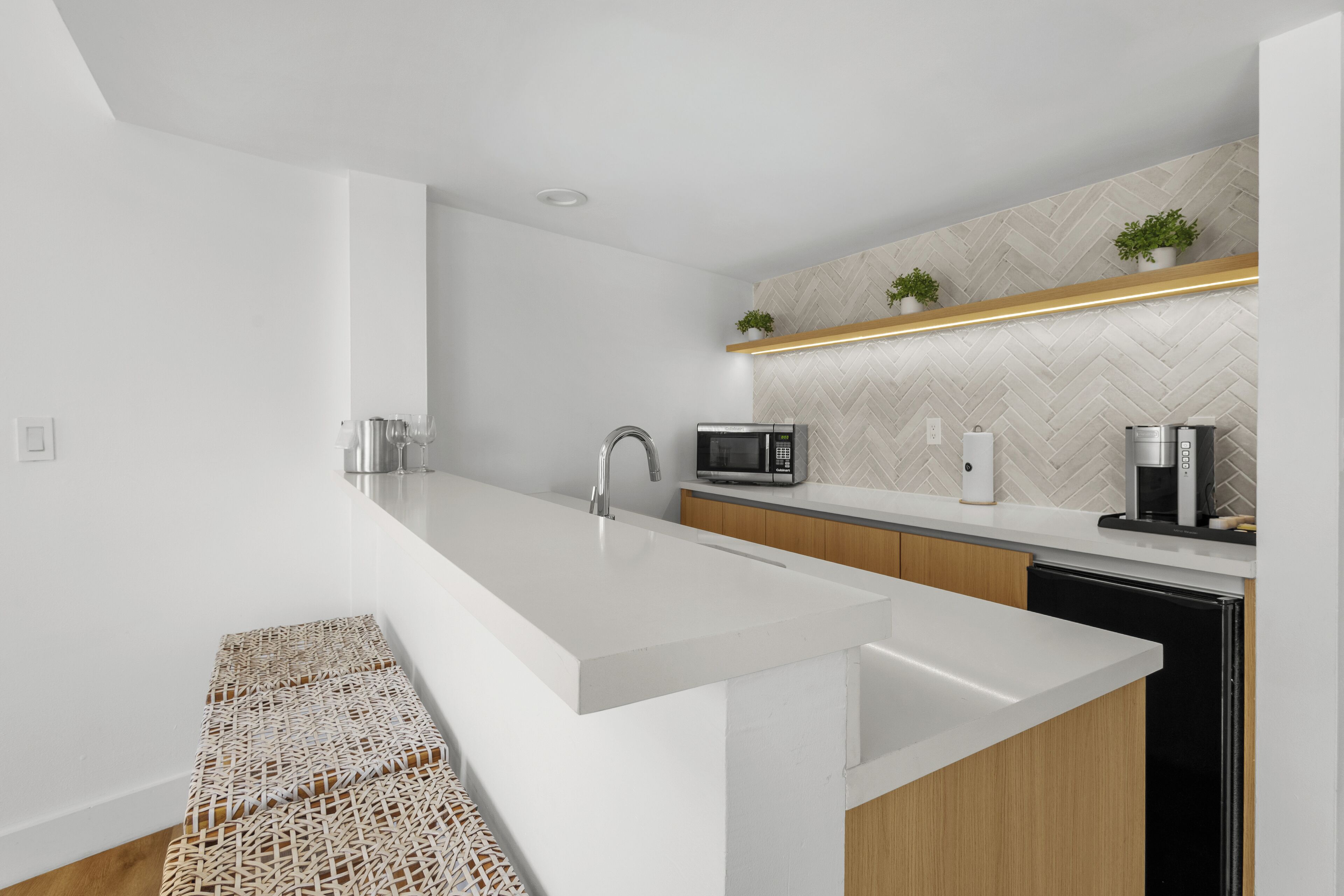 A modern kitchen with a white countertop, stainless steel appliances, and a herringbone-patterned backsplash.
