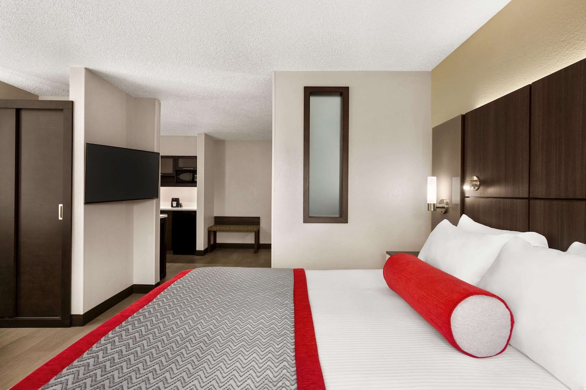 A hotel room with a large bed, a television, a desk, and a mirror.