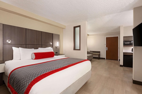 Una habitación de hotel con una cama grande, un escritorio y una kitchenette.
