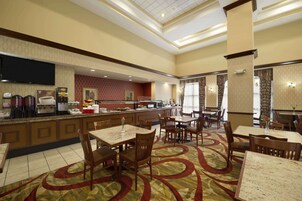 Ristorante di hotel con un'area bar centrale, tavoli e sedie.