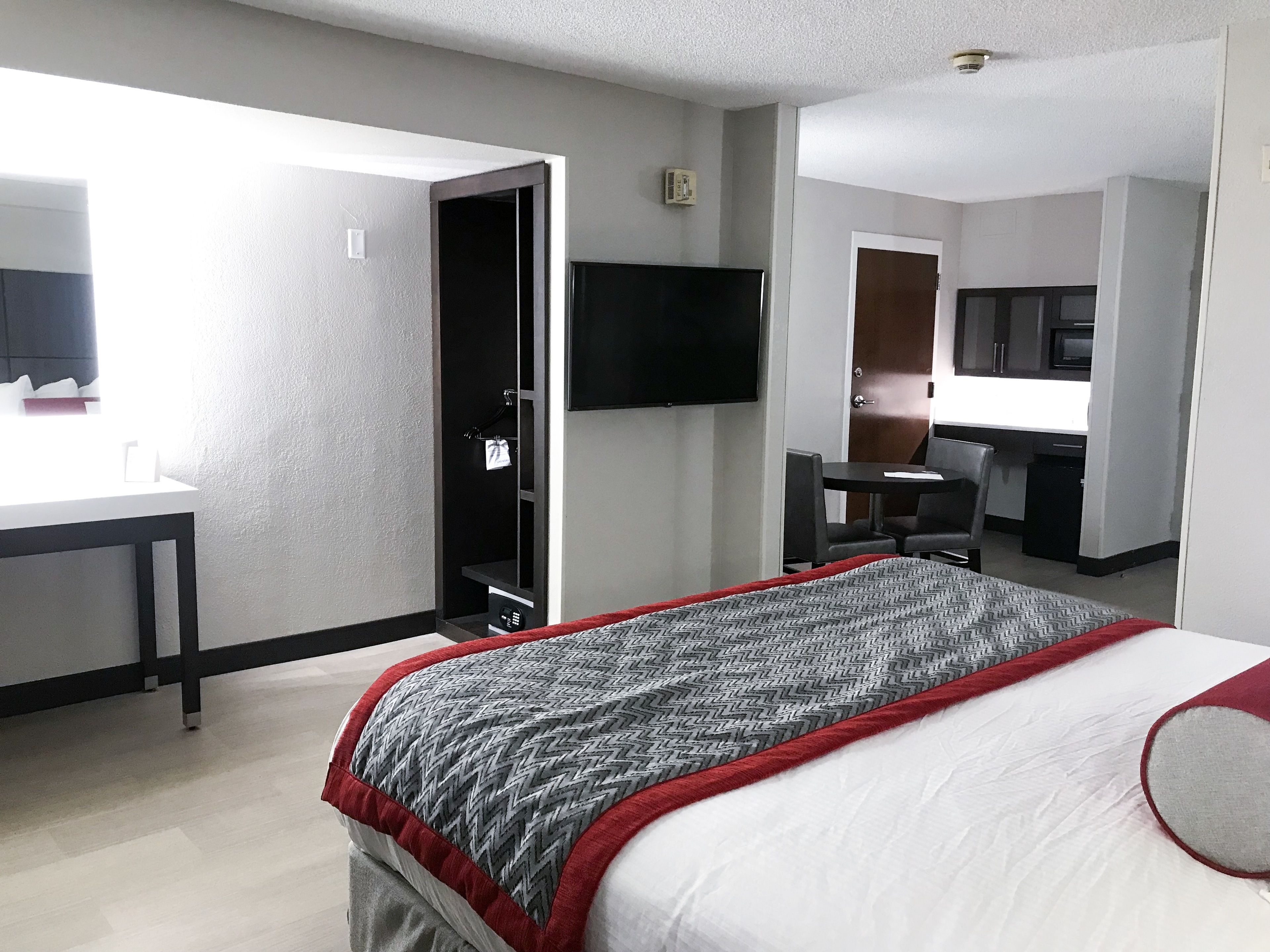 Een hotelkamer met een bed, een bureau, een stoel, een televisie en een deur naar een badkamer.