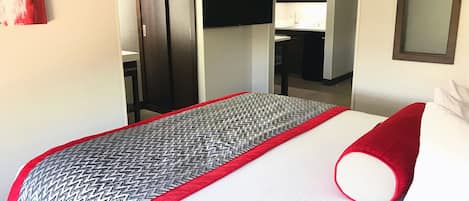 Quarto de hotel com cama, televisão na parede e guarda-roupa.