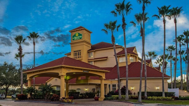 A hotel with a prominent tower, palm trees, and a red roof. - La Quinta Inn & Suites by Wyndham Orlando Airport (Orlando)