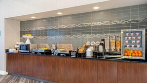 A buffet area with a microwave, coffee maker, and various food containers. - La Quinta Inn & Suites by Wyndham Orlando Airport (Orlando)