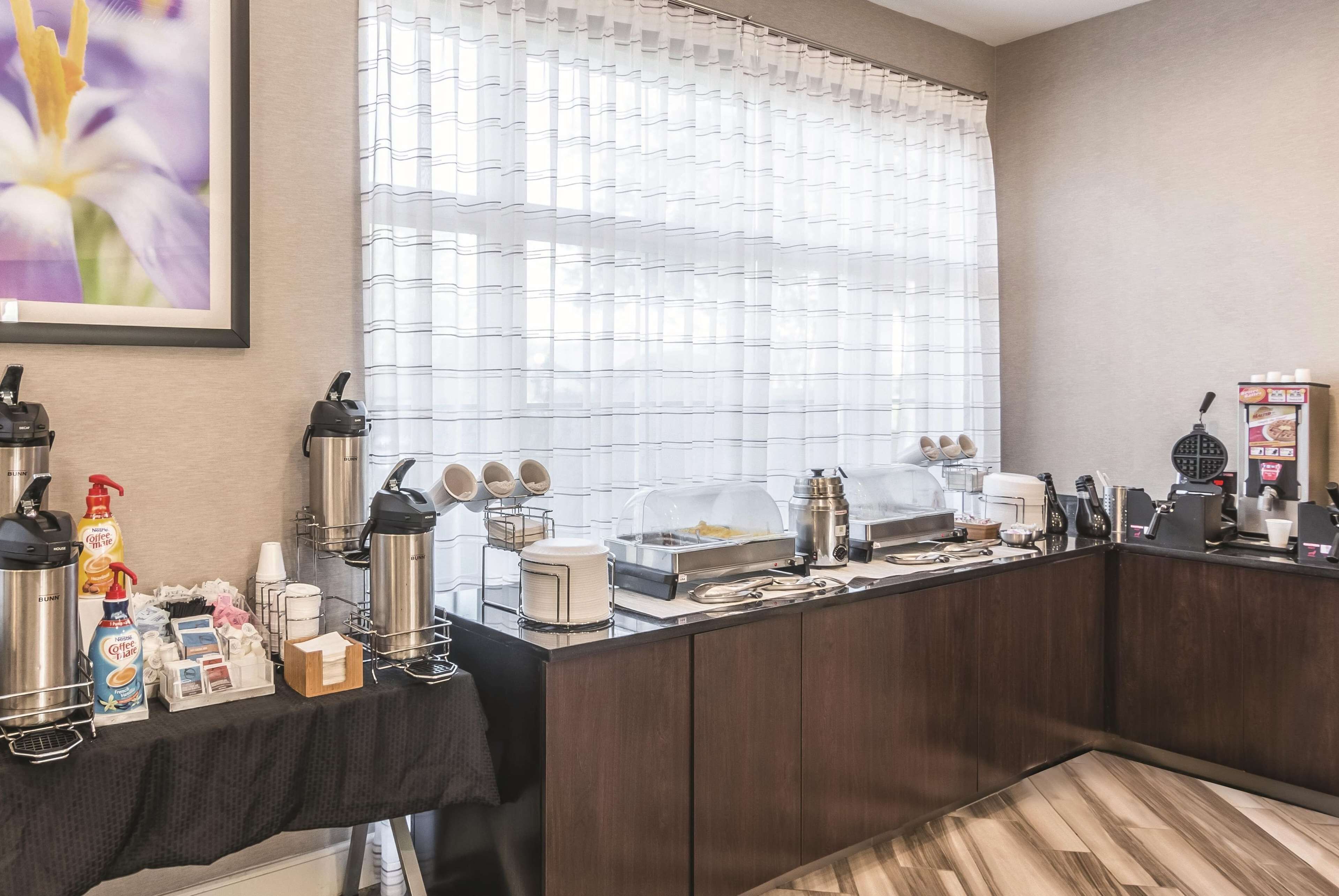 A hotel room with a kitchenette, including a coffee machine, tea maker, and various kitchen utensils.