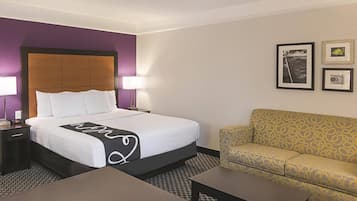 Une chambre d’hôtel avec un lit, un canapé, une table et une table de chevet.