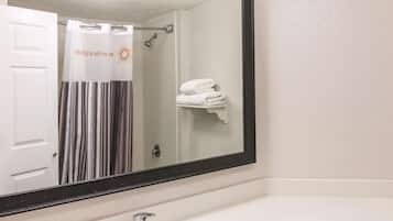 A bathroom with a large mirror, a white sink, and a towel rack with folded towels.