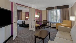 A hotel room with a bed, a desk, a chair, a sofa, and a TV. - La Quinta Inn & Suites by Wyndham Orlando Airport (Orlando)