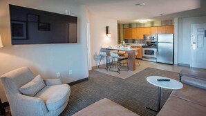A modern living room with a grey sofa, a small round table, and a TV mounted on the wall. - Residence Inn by Marriott Pensacola Downtown (Pensacola)