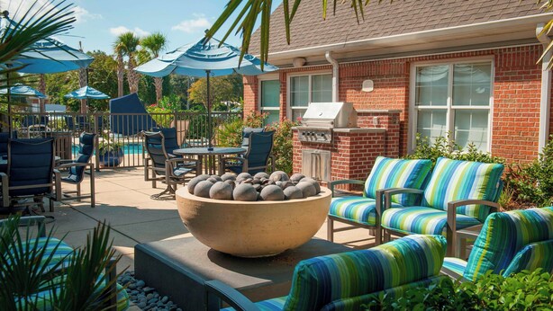 A patio area with outdoor furniture, a large stone bowl, and a grill. - Residence Inn by Marriott Pensacola Downtown (Pensacola)