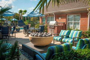 Un espace patio aménagé avec du mobilier d’extérieur, un grand récipient en pierre et un barbecue.