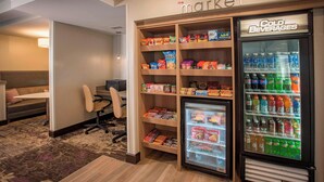 A hotel room with a kitchenette, a refrigerator stocked with snacks, and a vending machine with cold beverages. - Residence Inn by Marriott Pensacola Downtown (Pensacola)