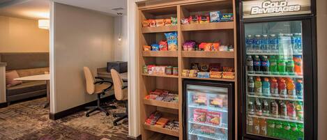 Ein Hotelzimmer mit einer Küchenzeile, einem mit Snacks gefüllten Kühlschrank und einem Getränkeautomaten mit kalten Getränken.