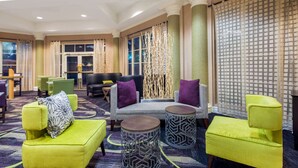 Un hall de hotel con un sofá, dos sillones y una mesa de centro.