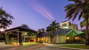 Un hotel con entrada cubierta, palmeras y un cartel de La Quinta.