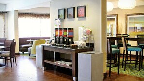 A hotel lobby with a coffee station, seating area, and artwork on the walls. - Hampton Inn Tampa/Rocky Point-Airport (Tampa)