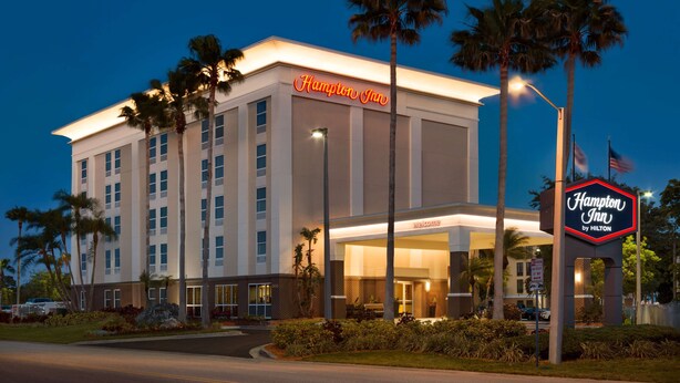 A Hampton Inn hotel with a well-lit entrance, palm trees, and a clear night sky. - Hampton Inn Tampa/Rocky Point-Airport (Tampa)