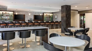 A modern bar area with a long counter, multiple bar stools, and a large flat-screen TV mounted on the wall. - DoubleTree by Hilton Atlanta Airport (Atlanta)