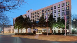 A multi-story hotel with a modern facade, a well-lit entrance, and a flagpole with flags. - DoubleTree by Hilton Atlanta Airport (Atlanta)