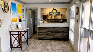 A reception desk with a Days Inn sign, a wooden reception desk, and a wall with framed pictures. - Days Inn by Wyndham Donalsonville (Donalsonville)