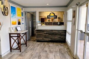 A reception desk with a Days Inn sign, a wooden reception desk, and a wall with framed pictures.