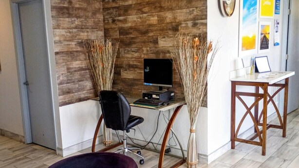 A room with a wooden wall, a desk with a computer, a chair, and a small table with a lamp. - Days Inn by Wyndham Donalsonville (Donalsonville)