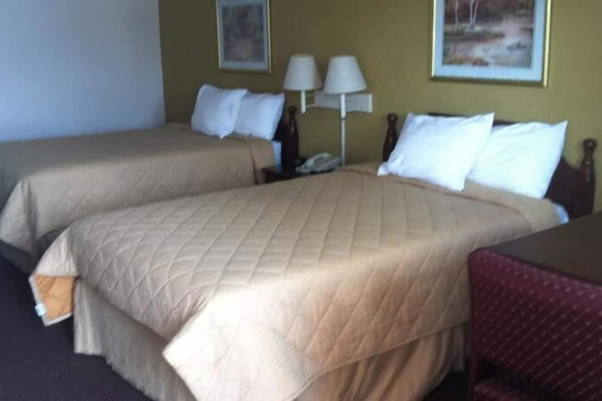 Habitació d'hotel amb dos llits, un escriptori, dues làmpades i una cadira.