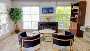 A room with a fireplace, a round marble table, three chairs, a bookshelf, and a large potted plant. - Days Inn by Wyndham Donalsonville (Donalsonville)