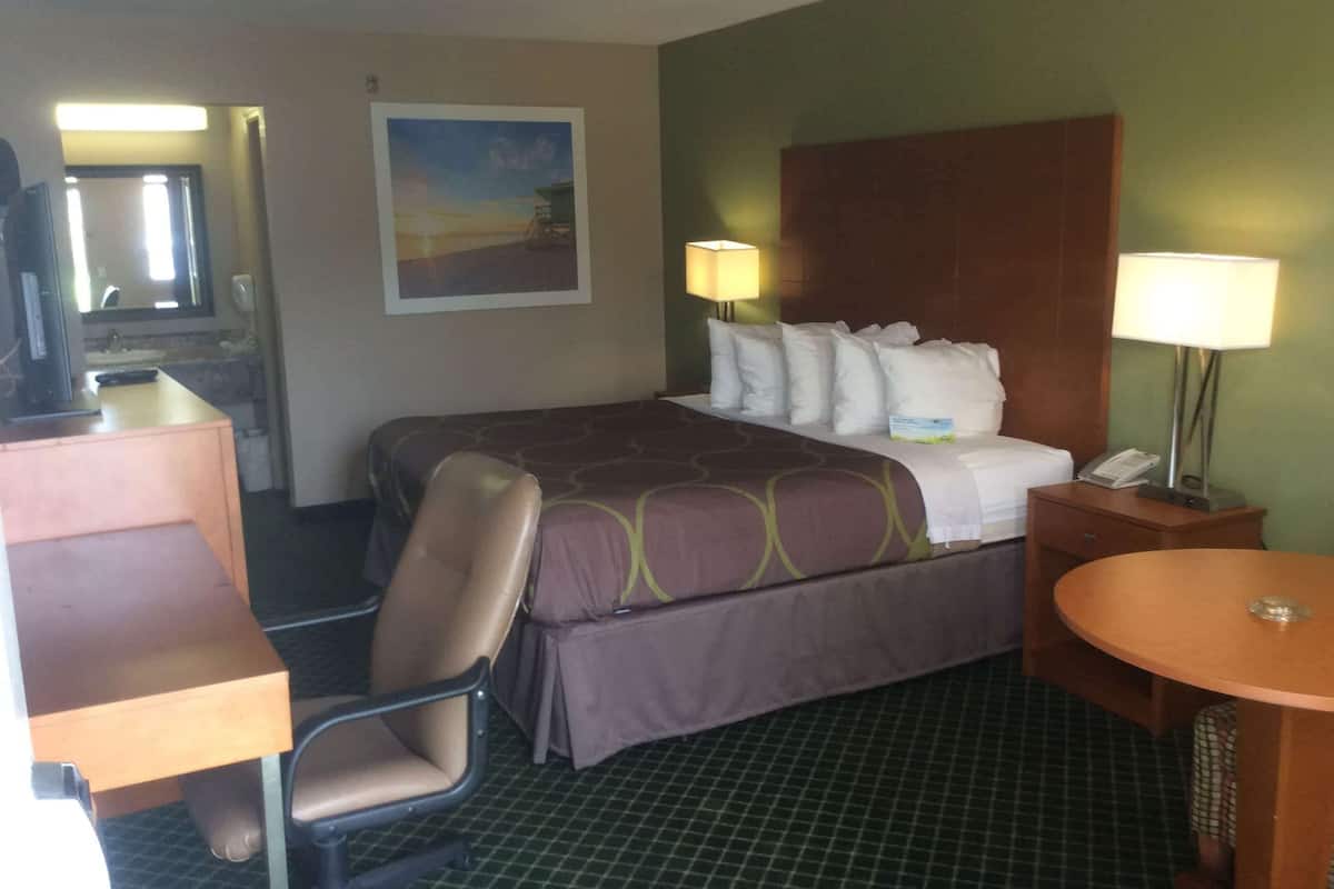 Habitació d'hotel amb un llit, dues làmpades de nit, una cadira, un escriptori i un quadre a la paret.