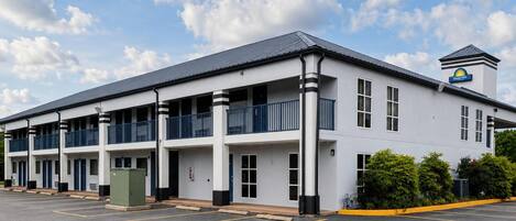 A Days Inn with a two-story structure, a covered parking area, and a clear sky.