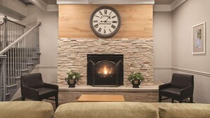 A living room with a fireplace, a clock, and a staircase.