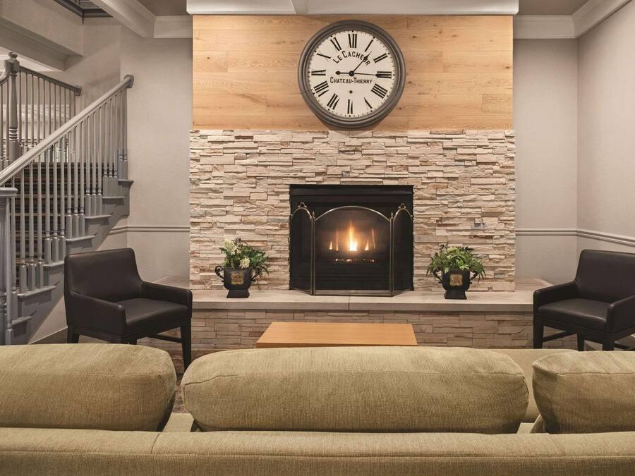 A living room with a fireplace, a clock, and a staircase.