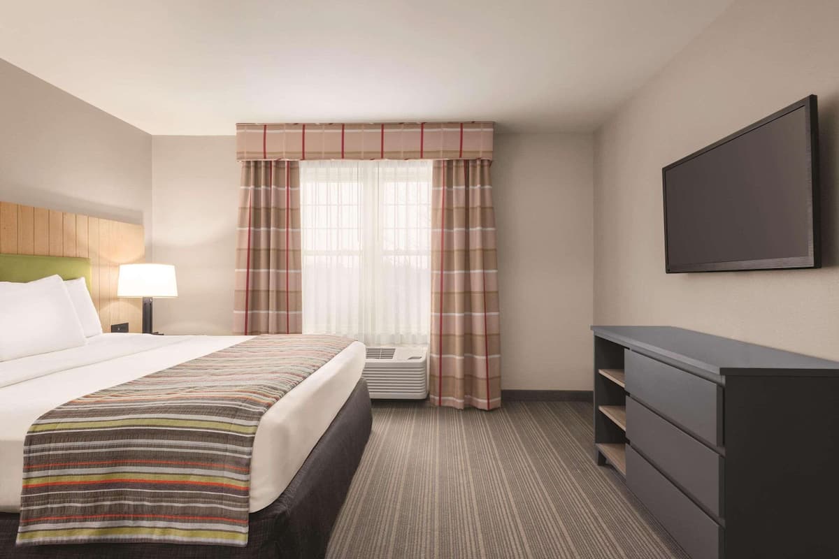 A hotel room with a bed, a desk, a chair, a television, and a window with curtains.