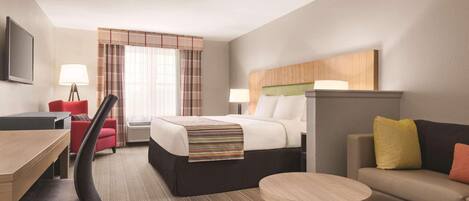 Quarto de hotel com cama, escrivaninha, cadeira, sofá e mesinha.
