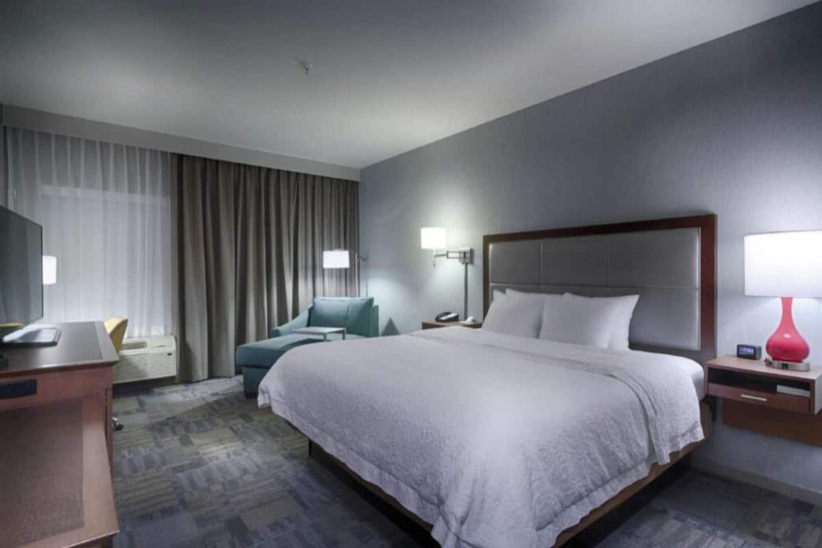 Une chambre d’hôtel avec un grand lit, un bureau, une chaise, une télévision et une lampe.