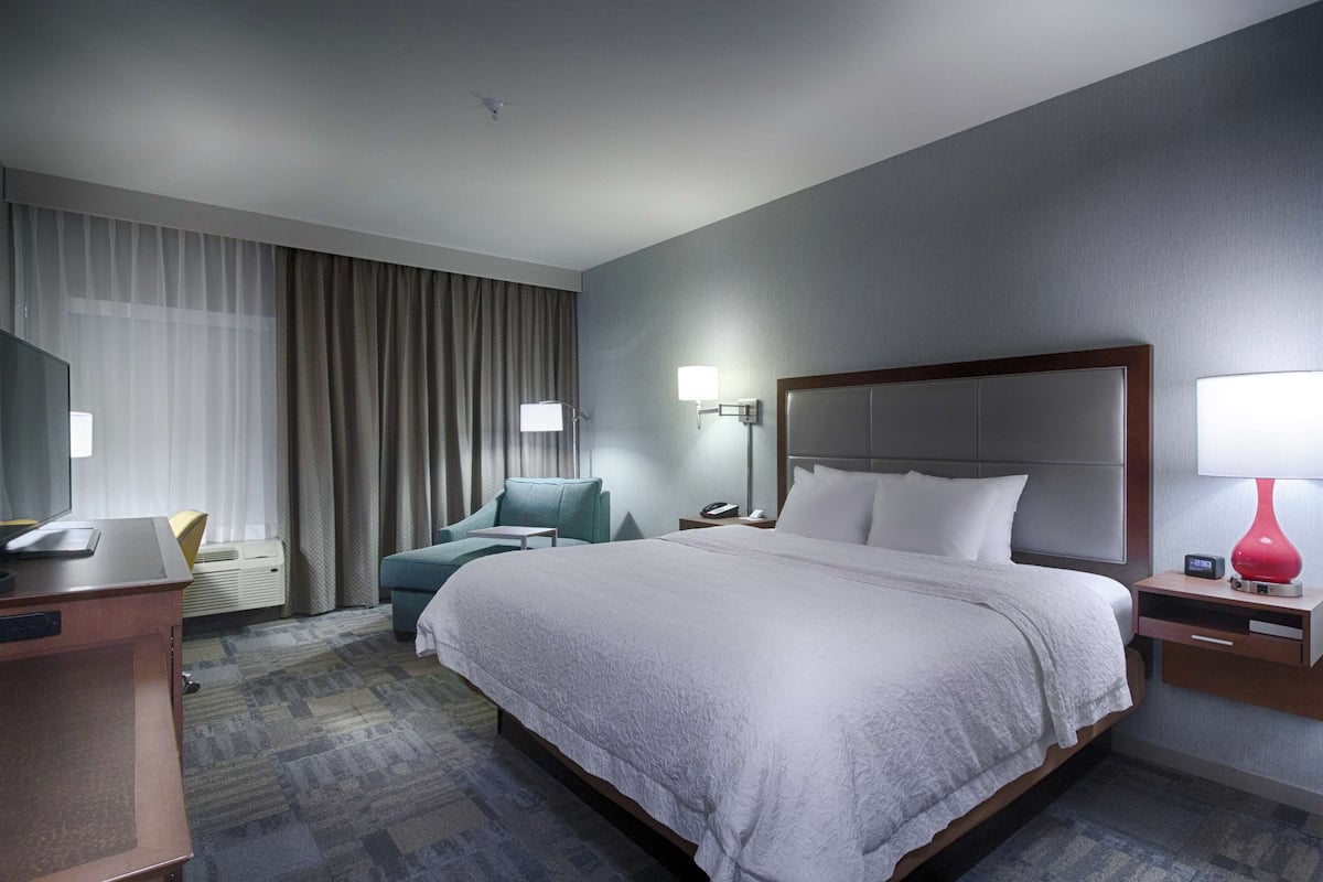 Une chambre d’hôtel avec un grand lit, un bureau, une chaise, une télévision et une lampe.