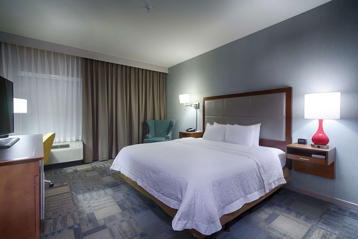 Une chambre d’hôtel équipée d’un lit, d’un bureau, d’une chaise, d’une télévision, d’une lampe et d’une table de chevet.