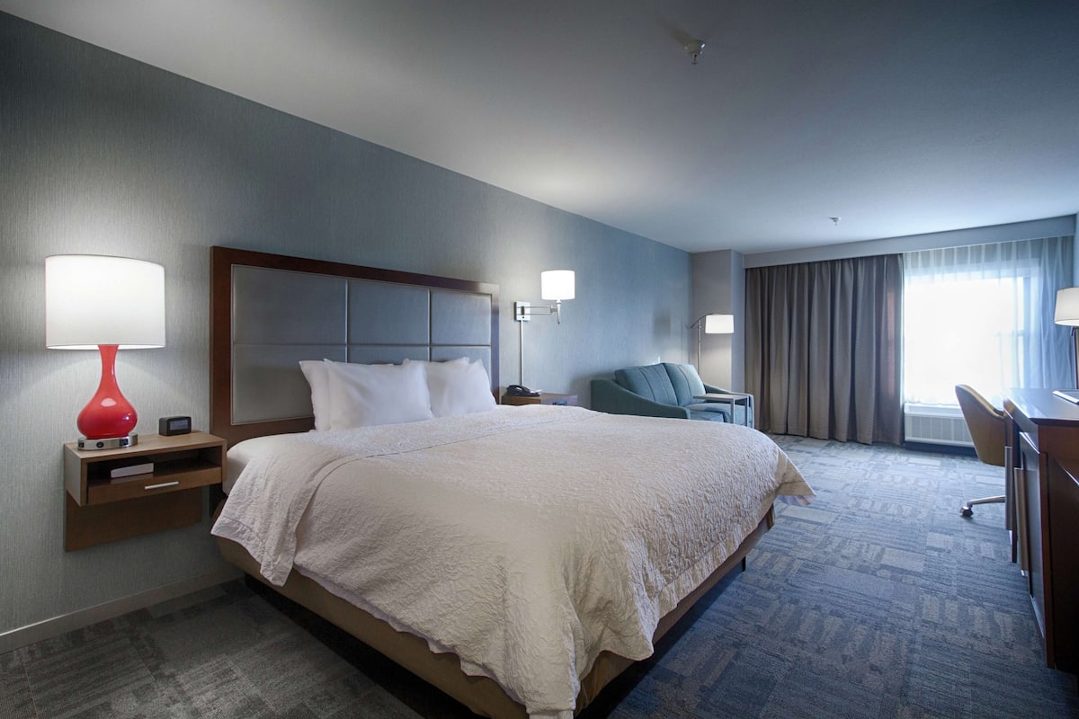 Une chambre d’hôtel avec un grand lit, un bureau, une chaise et une lampe.