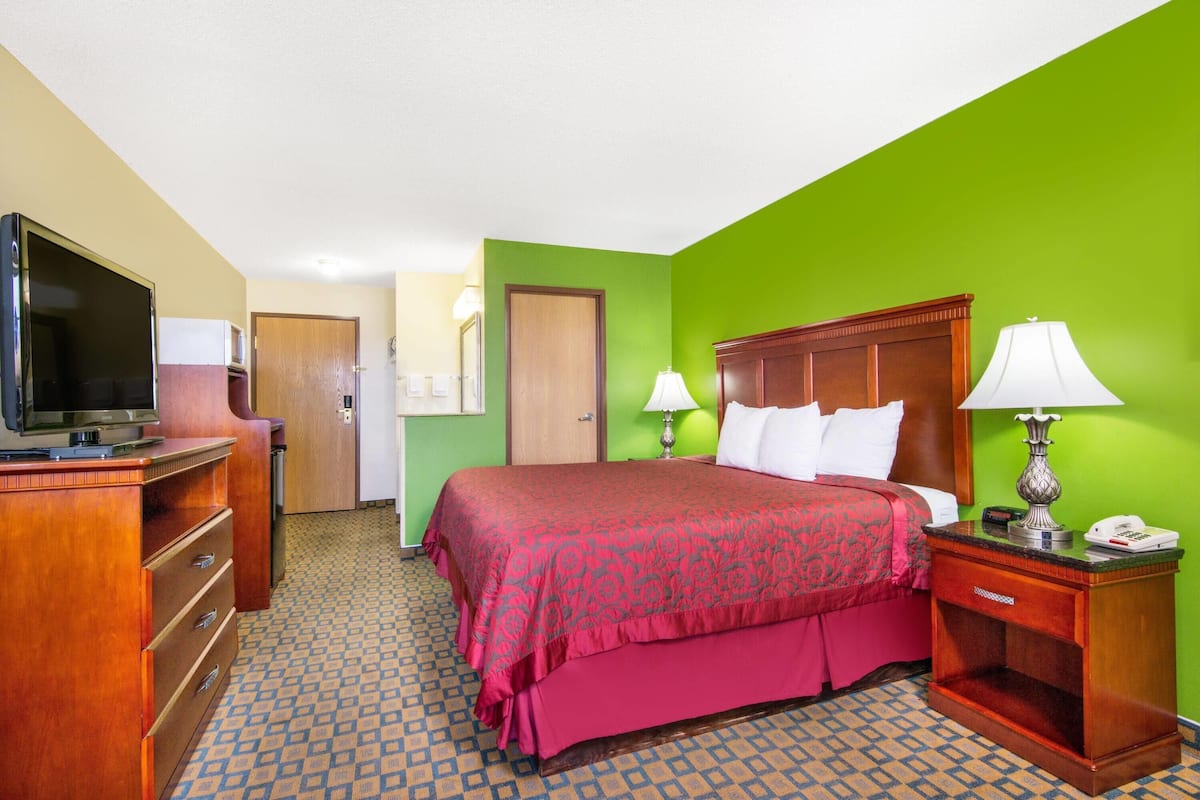 A hotel room with a bed, a television, a desk, and a lamp.