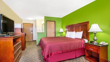 Una habitación de hotel con una cama, televisión, escritorio y lámpara.