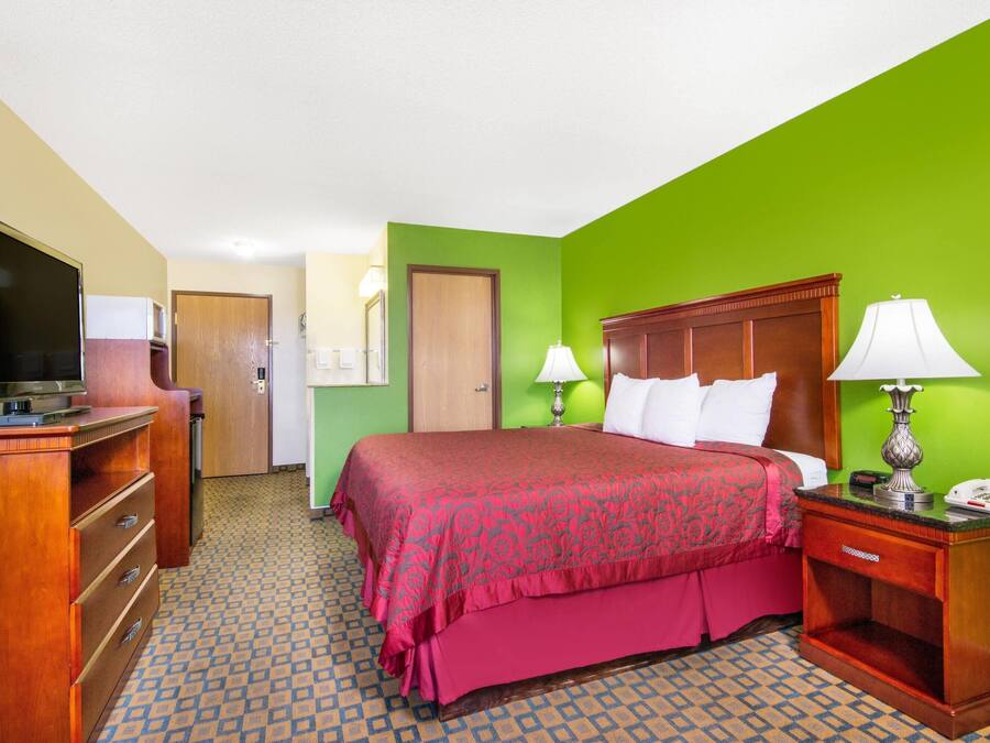 Una habitación de hotel con una cama, televisión, escritorio y lámpara.