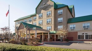 A Country Inn & Suites building with a green roof, multiple windows, and a parking lot. - Country Inn & Suites by Radisson, Lexington, KY (Lexington)