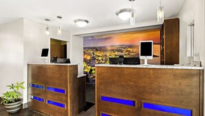 A reception area with two wooden reception desks, a cityscape mural, and a potted plant. - Best Western Paducah Inn (Paducah)